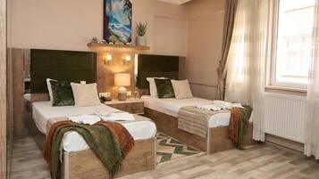 A hotel room with two single beds, a wooden headboard, a painting above the beds, a small shelf with decorative items, and a window with curtains.