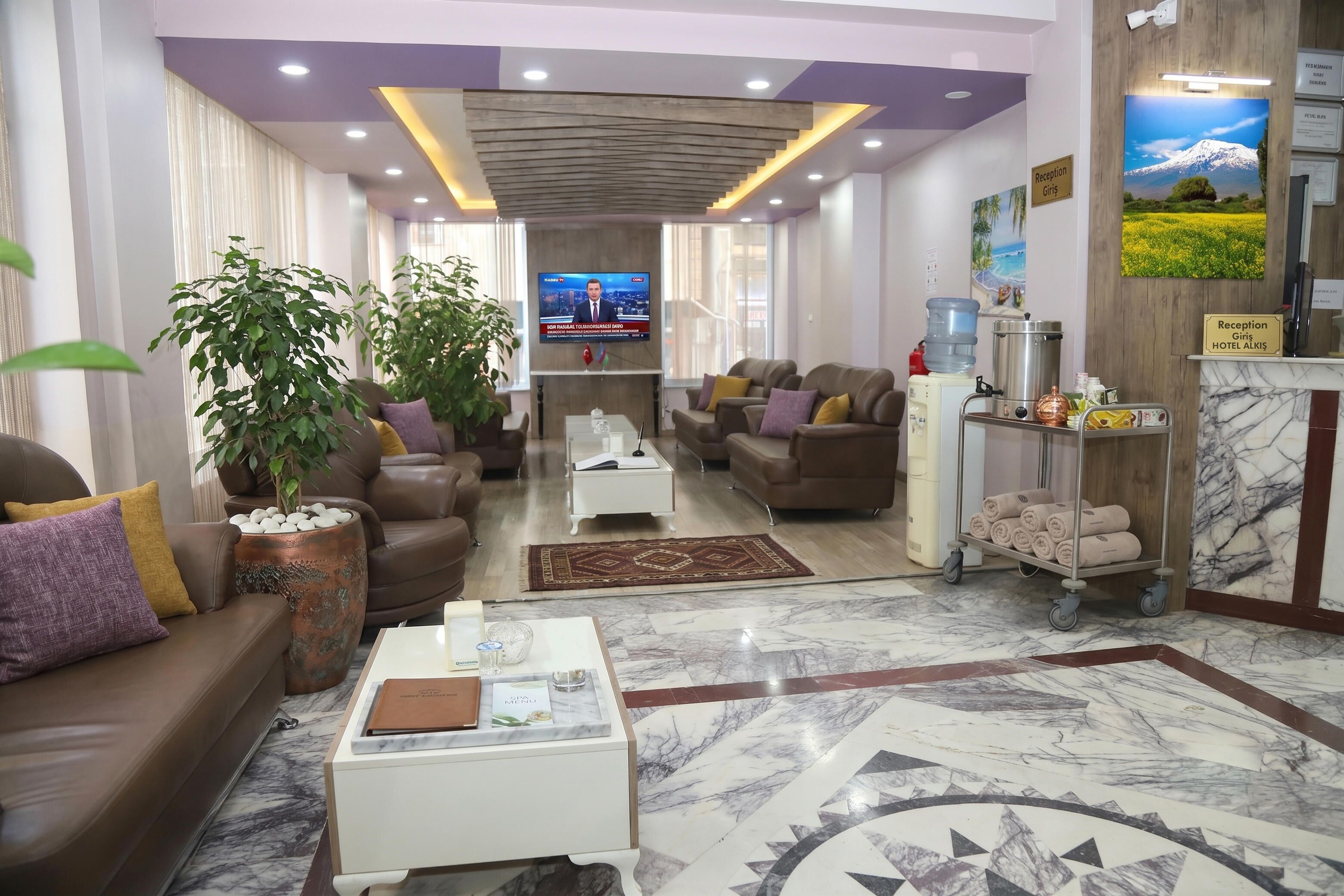 A hotel lobby with a reception desk, seating area, and a television screen.