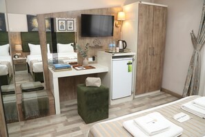 A hotel room with a bed, a desk with a computer, a television, a minibar, and a small seating area. - Alkış Otel (Igdir)