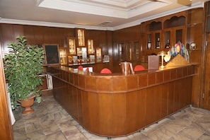 A wooden reception desk with a curved design, surrounded by glass display cabinets with various items.