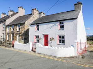 A two-story house with a red door, white walls, and a stone facade. - Pant (Llanfairpwllgwyngyll)