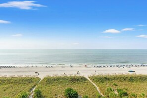 A beach with a clear sky, sandy shore, and a few umbrellas and beach chairs. - Luxury 2/2 Oceanfront at Sea Winds PH8 (North Myrtle Beach)