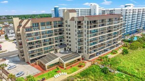 A multi-story hotel with a central courtyard, balconies, and a pool area. - Luxury 2/2 Oceanfront at Sea Winds PH8 (North Myrtle Beach)