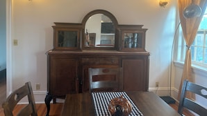 Une salle à manger avec une table en bois, des chaises, une nappe à carreaux et une citrouille décorative en guise de centre de table.