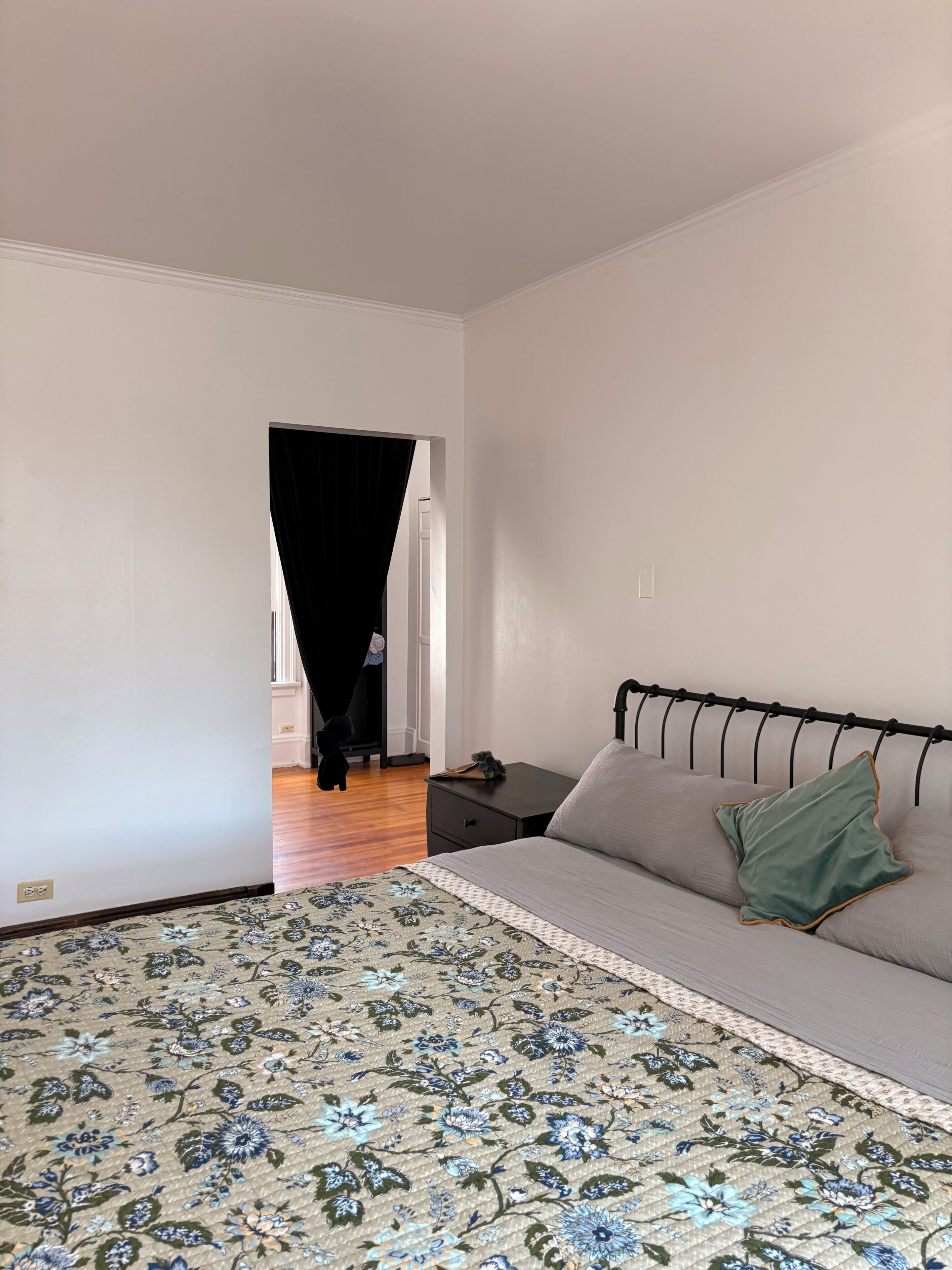 Une chambre à coucher comprenant un lit, une table de chevet, une commode et une porte donnant sur une autre pièce.
