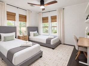 A hotel room with two beds, a desk, and a ceiling fan. - Oak & Ash | Lindale Park Houston (Houston)