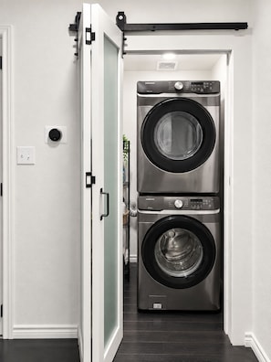 A laundry room with two stacked front-loading washing machines. - Oak & Ash | Lindale Park Houston (Houston)