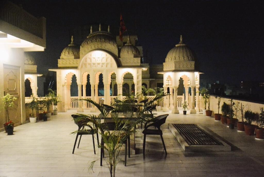 A courtyard with a building featuring domed architecture, potted plants, and outdoor seating.
