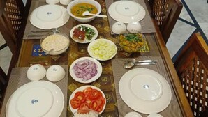 A dining table set with plates, bowls, and cutlery, surrounded by chairs.
