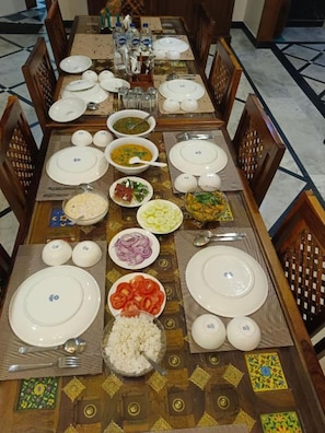 Una mesa de comedor dispuesta con platos, tazones y cubiertos, rodeada de sillas.