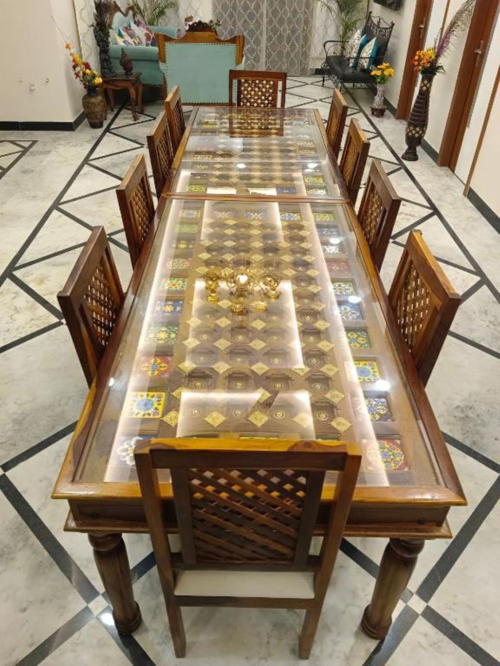 A rectangular dining table with a glass top and wooden chairs.