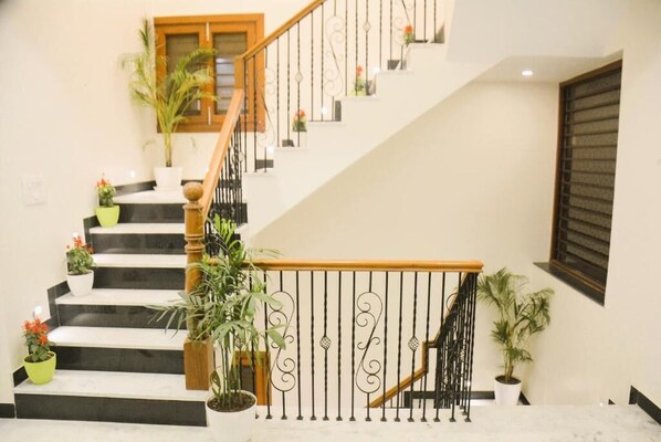 A staircase with black steps, wooden handrails, and decorative metal railings.