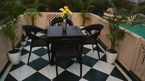A terrace with a checkered floor, a table with chairs, and potted plants.