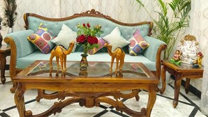 A room with a sofa, a glass-top coffee table, and a small wooden side table with decorative items.