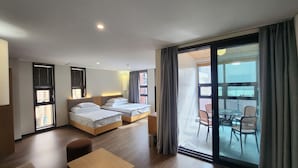 Una habitación de hotel con dos camas, un balcón con sillas y una mesa.
