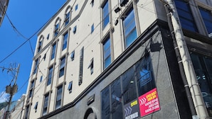Un edificio de varios pisos con entrada visible, un letrero que indica zona de juegos recreativos y una señalización que prohíbe el estacionamiento.