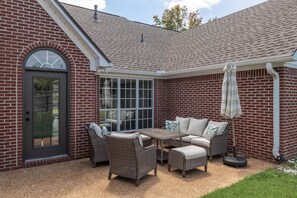 A brick house with a covered patio area featuring wicker furniture and a table. - Tanner Drive Getaway | Pet Friendly (Oxford)
