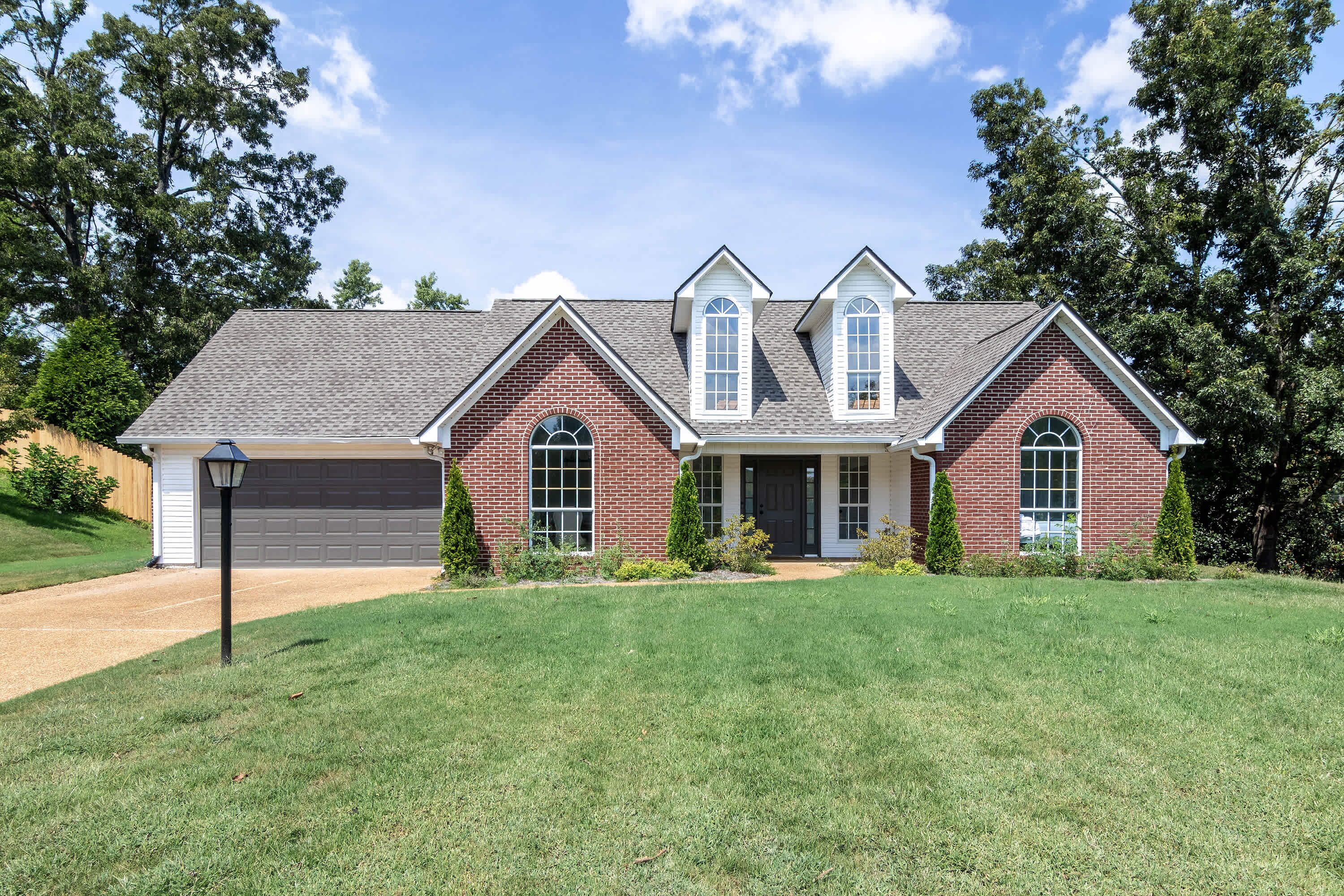A two-story house with a garage, a front porch, and a well-maintained lawn.