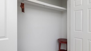 A white closet with a hanging rod and a small red table. - Tanner Drive Getaway | Pet Friendly (Oxford)