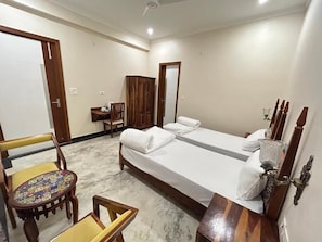 Quarto com cama, duas cadeiras, uma mesinha e um guarda-roupa.