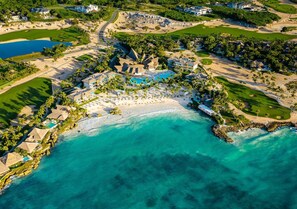 Eine Vogelperspektive eines Küstenresorts mit Strand, Golfplatz und Poolbereich.