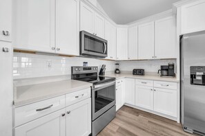 A modern kitchen with white cabinetry, stainless steel appliances, and a wood floor. - 🦀Seabreeze | Walk to Beach | Community Pool | 3BR🌅 (Panama City Beach)