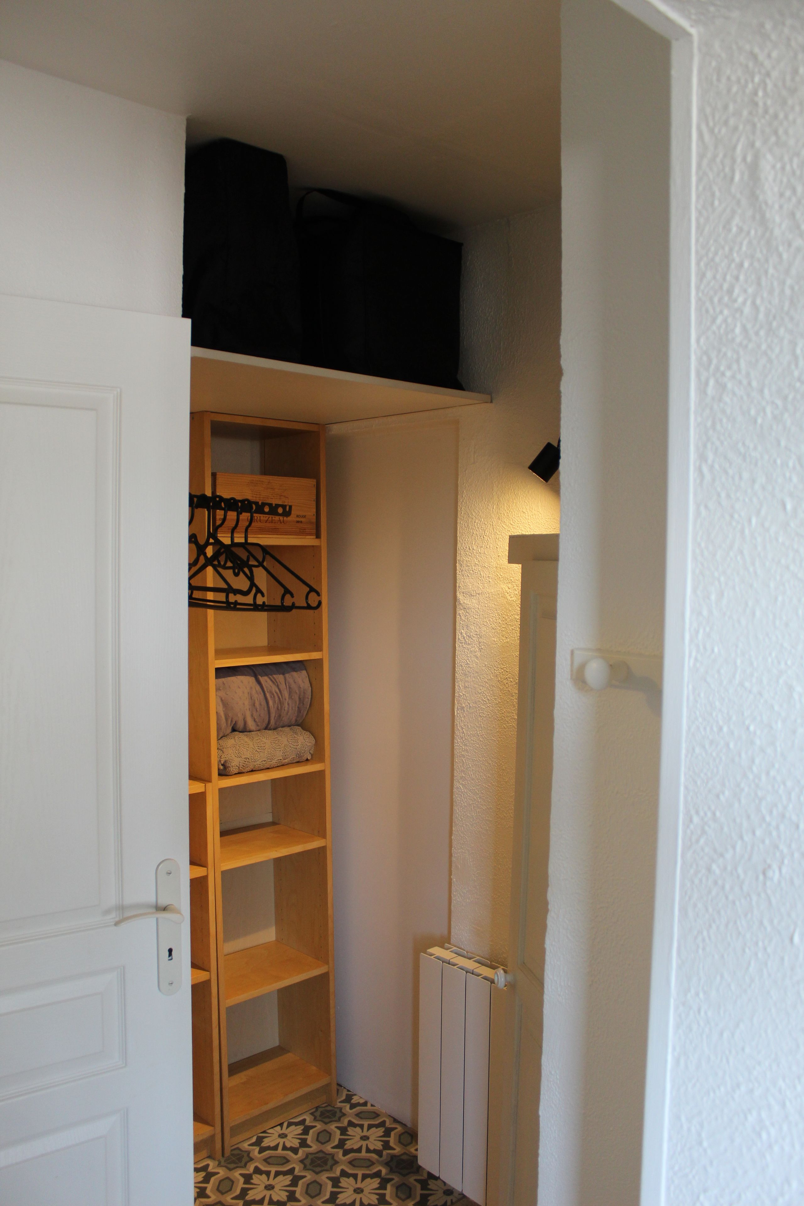 A narrow hallway with a wooden wardrobe, a radiator, and a door with a keyhole.