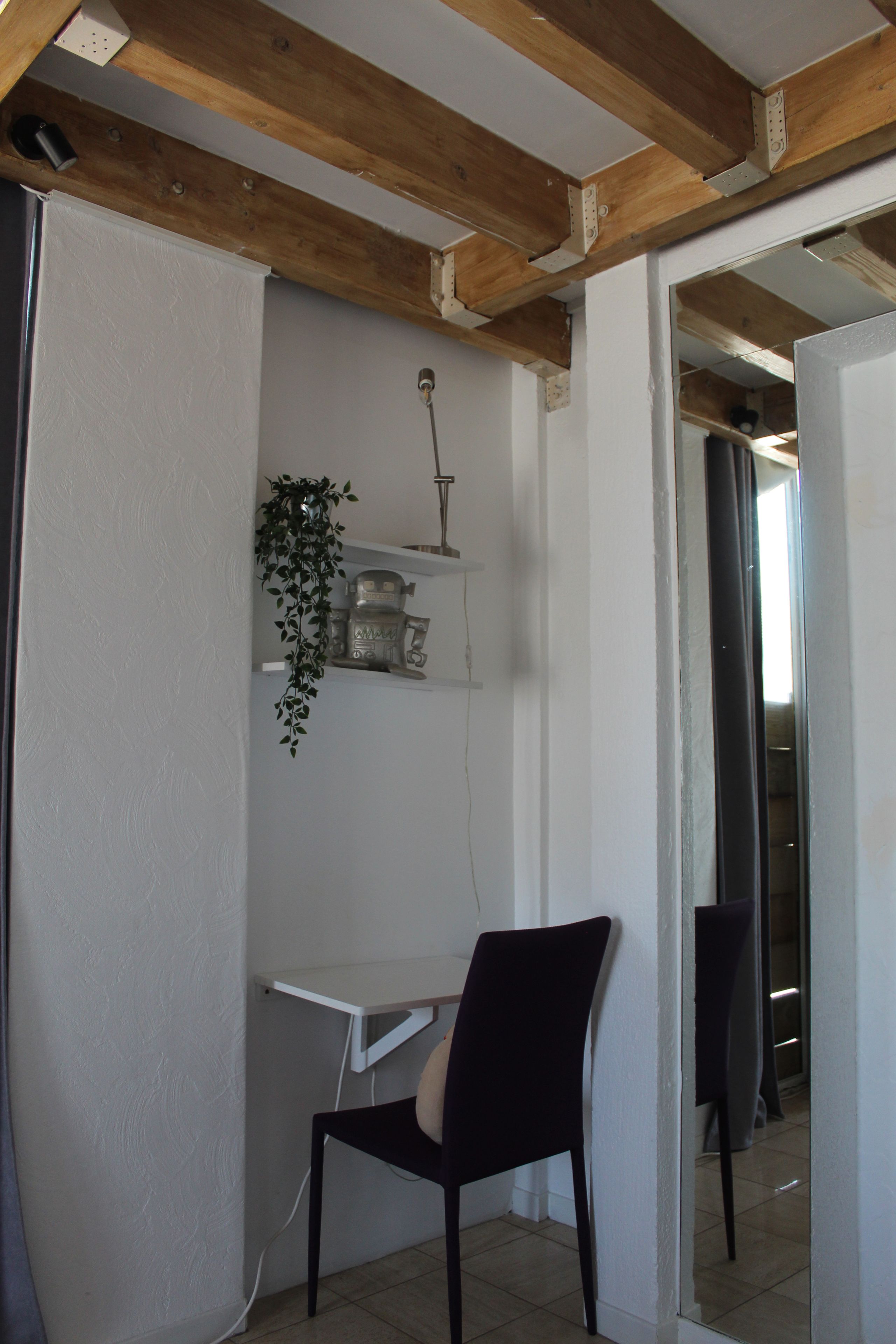 Ein Zimmer mit Schreibtisch, Stuhl und einer hängenden Pflanze.