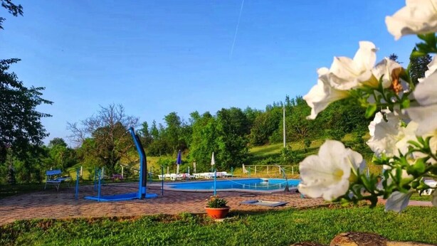 A park with a swimming pool, exercise equipment, and a grassy area.