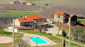 A residential property with a swimming pool, a tennis court, and a stone building.