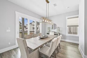A dining area with a wooden table, chairs, and a pendant light. - The Lookout | Rooftop Hot Tub | 4 Bikes | Community Pool! (Inlet Beach)