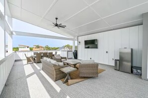 A covered outdoor area with seating, a television, and a refrigerator. - The Lookout | Rooftop Hot Tub | 4 Bikes | Community Pool! (Inlet Beach)