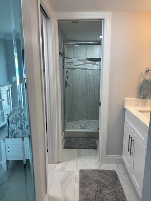 A bathroom with a glass-enclosed shower, a white sink, and a towel rack. - The Shores Condos - BEST in the Building!  TRUE Beachfront - End Unit! (Fort Myers Beach)