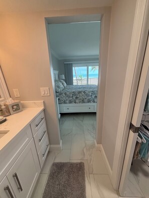 A narrow hallway leading to a bedroom with a bed, a nightstand, and a view of the beach. - The Shores Condos - BEST in the Building!  TRUE Beachfront - End Unit! (Fort Myers Beach)