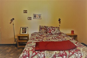 A bedroom with a bed, two bedside tables, a floor lamp, and framed pictures on the wall. - Cozy unique 2-bedroom townhome in THE HILLS  of San Isidro de GRECIA (SAN ISIDRO de Grecia)