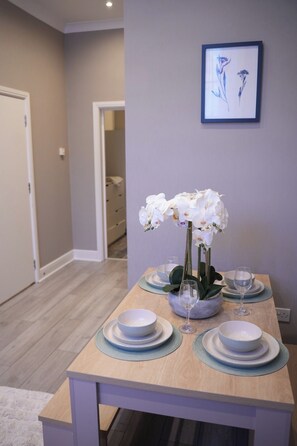 A dining table with white plates, blue placemats, and a vase of white orchids. - Camden,Euston,kingcross Family Apartment (London)