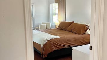 Een slaapkamer met een bed, een plafondventilator, een raam en een deur.