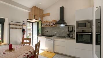 Een moderne keuken met witte kastjes, een inbouwoven, een magnetron en een koffiezetapparaat.