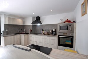 A modern kitchen with a built-in microwave, oven, and coffee maker.