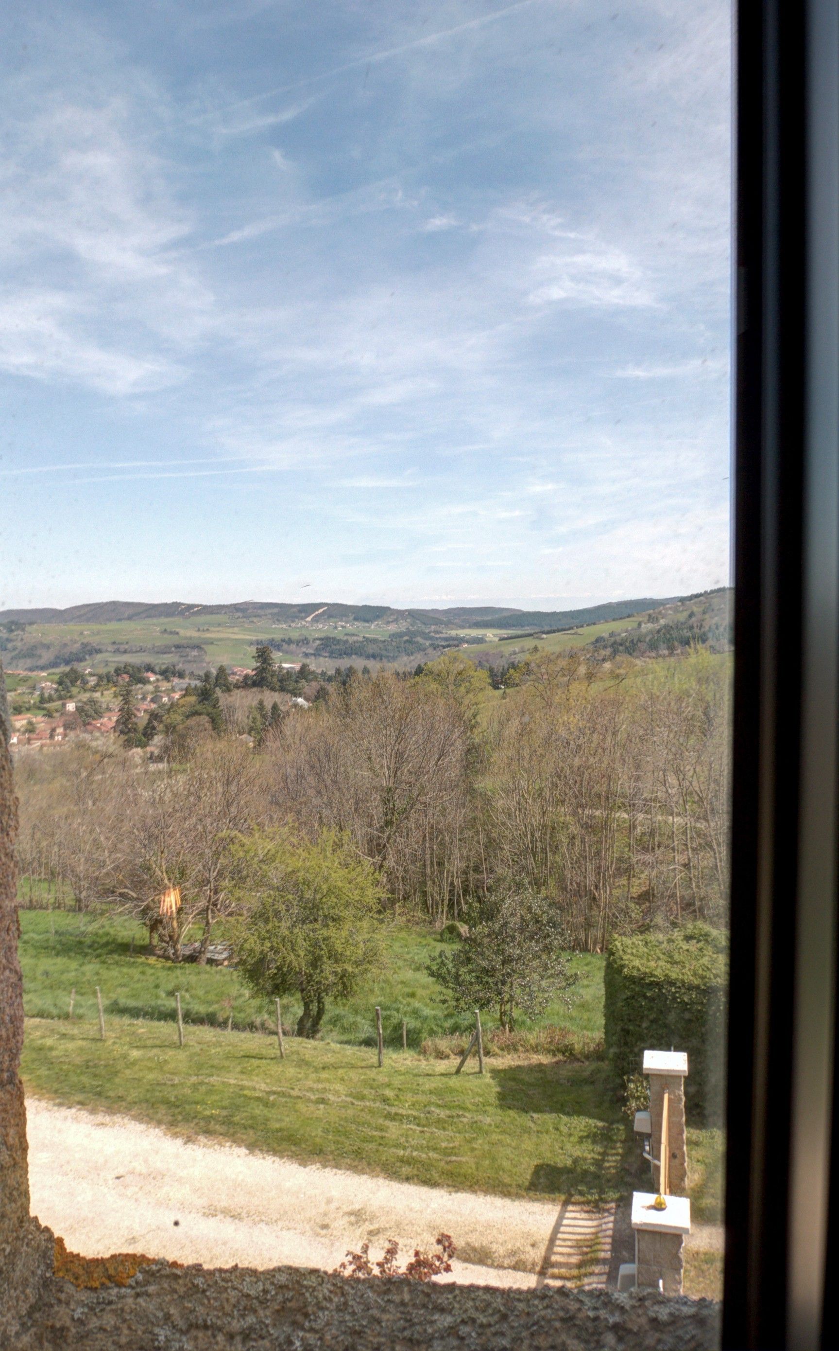Ein Blick auf eine ländliche Landschaft mit einem Feldweg, Bäumen und einem in der Ferne liegenden Dorf.
