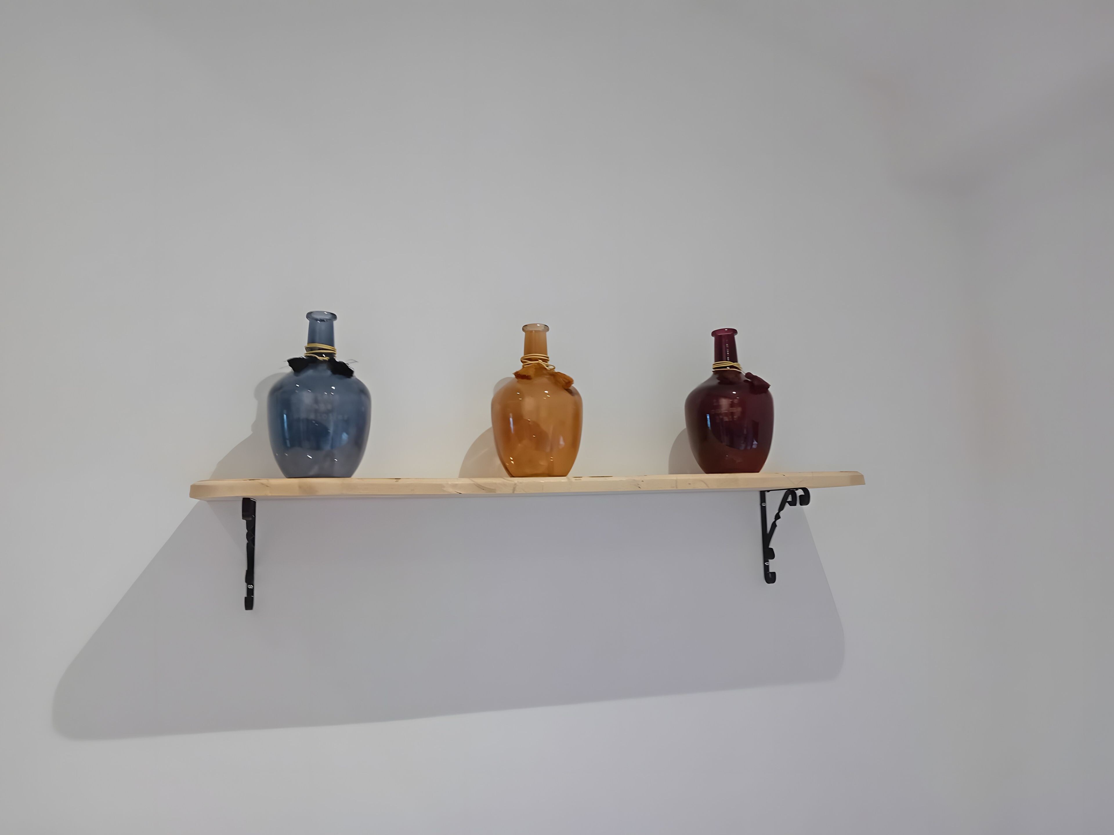 Una estantería con tres botellas de vidrio.