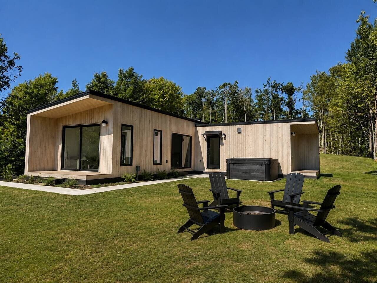 A modern wooden cabin with a patio area, outdoor seating, and a fire pit.