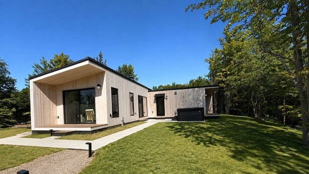 Et moderne hus med et stort glasvindue, en beton terrasse og en velplejet græsplæne.