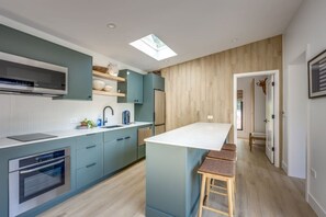 Una cocina moderna con una isla central, electrodomésticos integrados y un tragaluz.