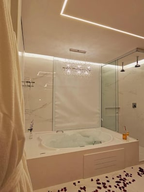 A modern bathroom with a large bathtub, a glass shower enclosure, and a vanity with a mirror. - Pousada Pinhão e Poesia (Canela)