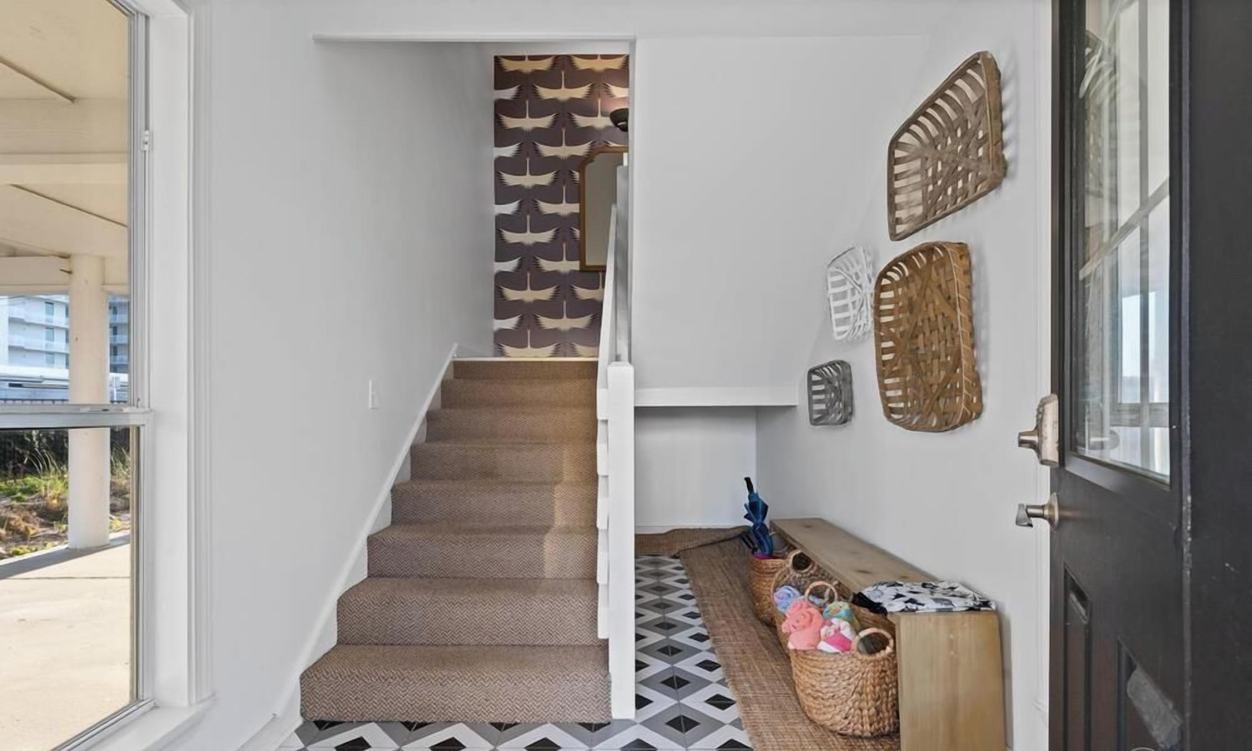 Una escalera con papel tapiz estampado, un banco y decoración en la pared.
