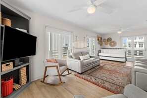 Una sala moderna con un televisor de pantalla plana, un sofá, un sillón mecedor y una alfombra estampada.