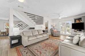 Una sala de estar moderna con un sofá, una mesa de centro, un televisor y una escalera.
