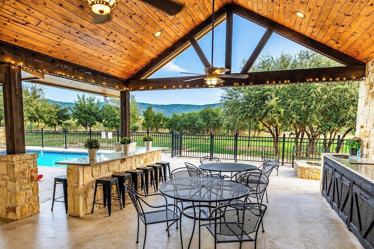 Eine Außenpatio mit Pool, Steinpfeilern, Metallmöbeln und Blick auf die Landschaft.