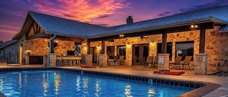 A poolside area with a stone building, outdoor seating, and a clear sky.